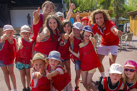 Niños y animadores sonrientes con pulgares arriba durante una actividad en el camping CAPFUN Emeraude en Portiragnes (34).