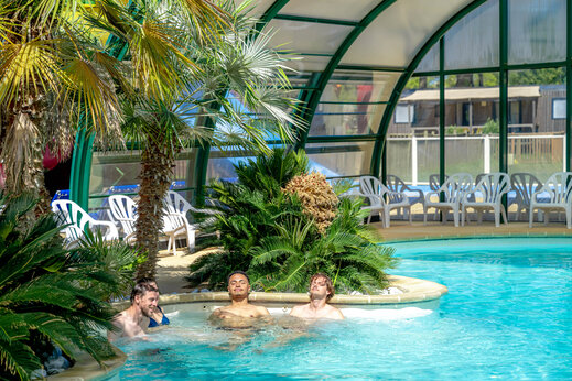 Jacuzzi y piscina cubierta con palmeras en el camping CAPFUN Grand Large en FOUESNANT.