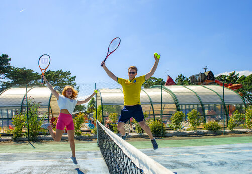 Cancha de tenis y jugadores saltando en el camping CAPFUN Grand Large en FOUESNANT (29).