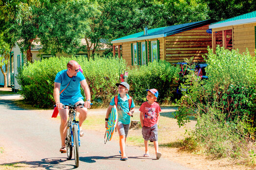 Familia en bicicleta y Mobil-homes al camping CAPFUN Huttes en Saint-Denis d'Oléron.