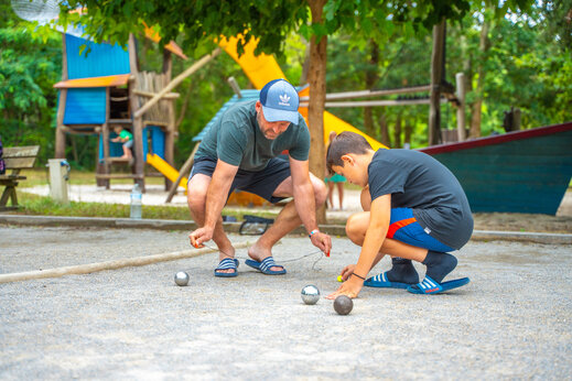 Padre e hijo juegan a la petanca en el camping CAPFUN Mer en Labenne-Océan.