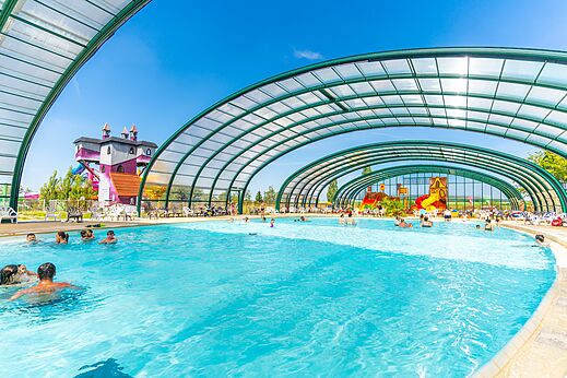 Piscina cubierta y toboganes acuáticos con juegos en el camping CAPFUN Mirabelle en VOLSTROFF (57).