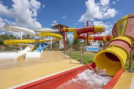 Toboganes acuáticos coloridos y niño deslizándose en el camping CAPFUN Paradis de Bazas en BAZAS (33).