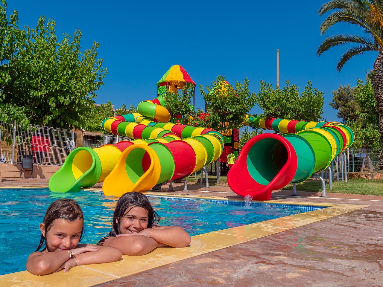 Ni�as sonrientes en la piscina con toboganes acu�ticos en el camping CAPFUN Alba en CREIXELL (43).