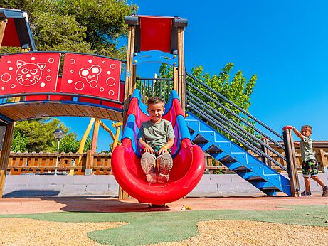 Tobogán y área de juegos colorida con niños sonrientes en el camping CAPFUN Alba en CREIXELL (43).