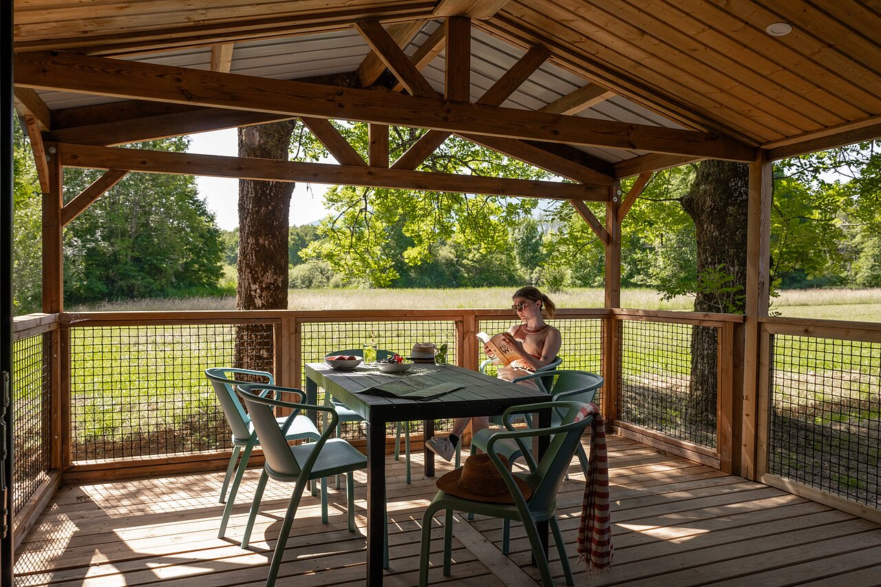 Terraza cubierta de madera de un Mobil-home, mujer leyendo, camping CLICOCHIC Aloua Sevrier.