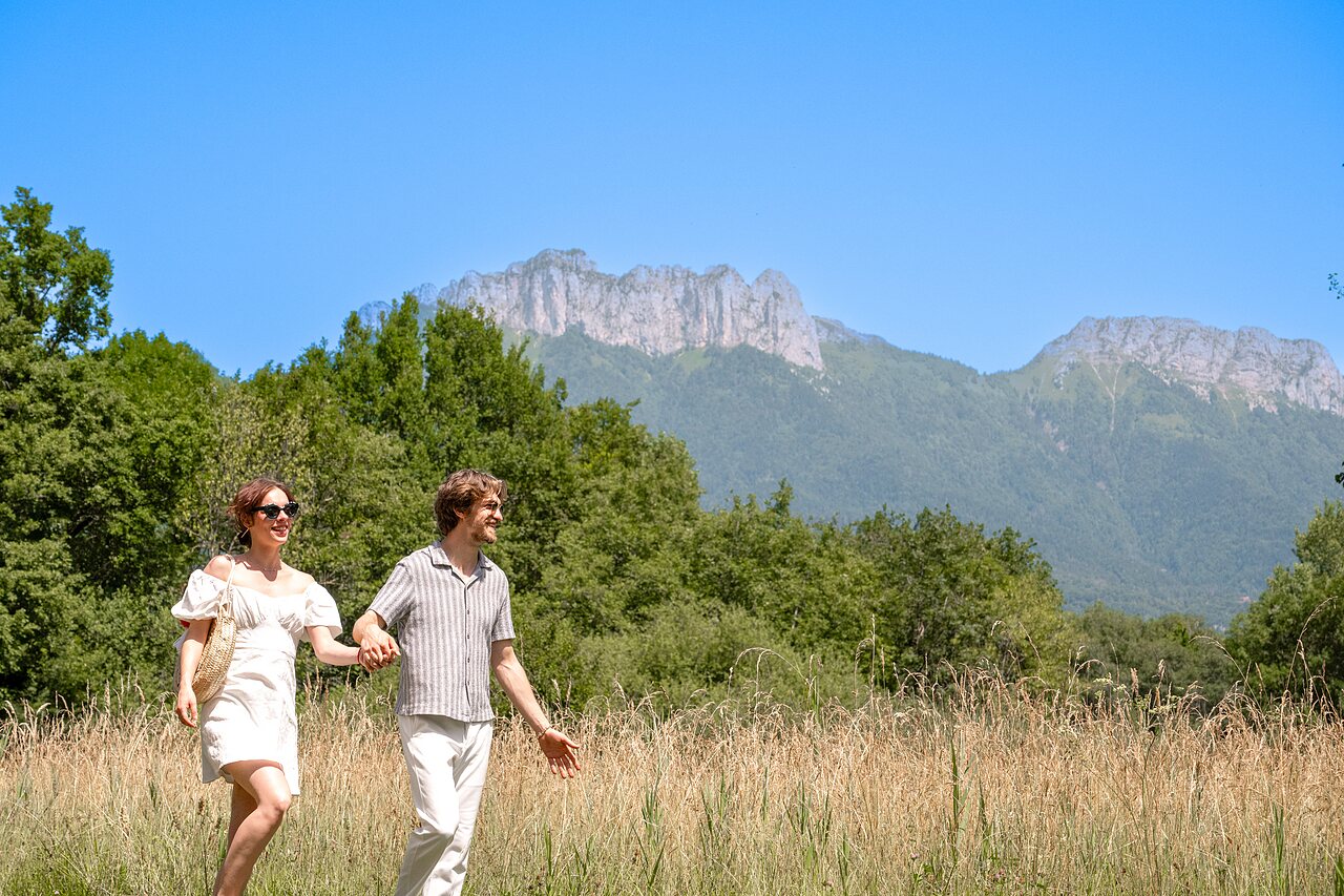 Pareja paseando, montañas de fondo en el camping CLICOCHIC Aloua en Sevrier (74).