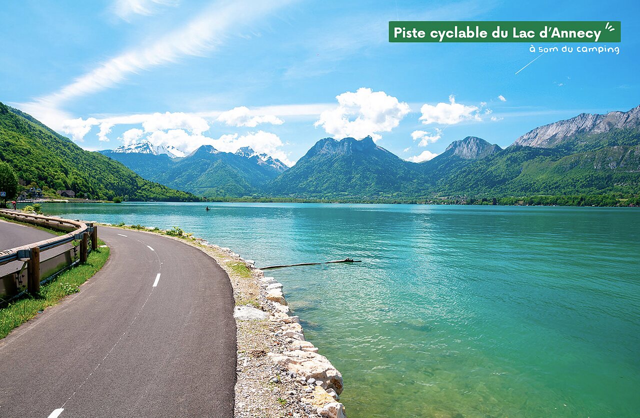 Carril bici junto al lago de Annecy, montañas verdes y nevadas al fondo.