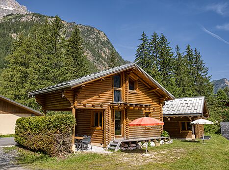 Mobil-home de madera con terraza y sombrilla en el camping CLICOCHIC Alpes Lodges en Pralognan.