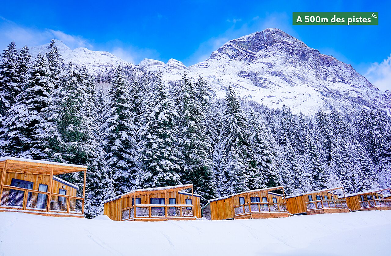 Mobil-homes de madera nevados, monta�as y bosque en camping CLICOCHIC Alpes Lodges Pralognan la Vanoise.