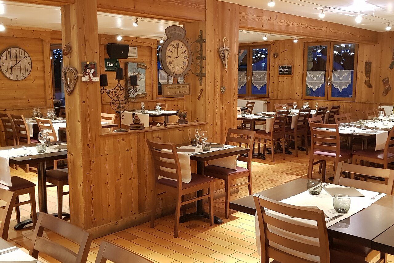 Interior acogedor del restaurante con mesas y sillas de madera en el camping CLICOCHIC Alpes Lodges en Pralognan la Vanoise (73).