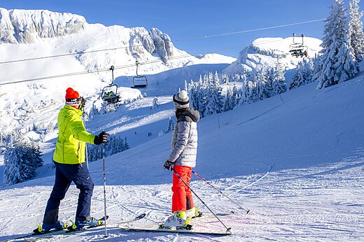 Esquiadores en pista nevada, telesilla, montañas en camping CLICOCHIC Alpes Lodges.