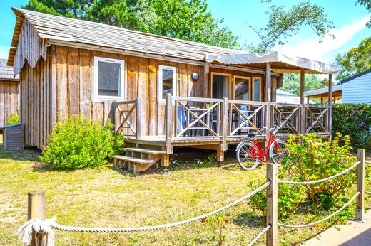 Mobil-home de madera con terraza cubierta y bicicleta en CAPFUN An Trest SARZEAU (56).
