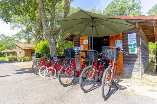 Bicicletas rojas en alquiler frente al punto de alquiler en el camping LIBRANOO Naturiste Arnaoutchot en Veille-Saint-Girons, Landes, Francia.
