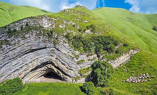 Montañas verdes, formación rocosa, ovejas en el camping LIBRANOO Naturiste Arnaoutchot en Veille-Saint-Girons, Landas, Francia.