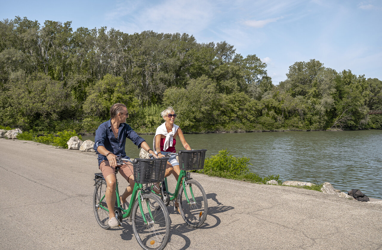 Pareja en bicicleta junto a un r�o, naturaleza exuberante en el camping CLICOCHIC Art de Vivre en Ch�teauneuf du Pape (84).