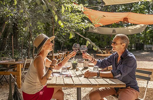 Pareja brindando en el restaurante exterior sombreado del camping CLICOCHIC Art de Vivre en Ch�teauneuf du Pape.