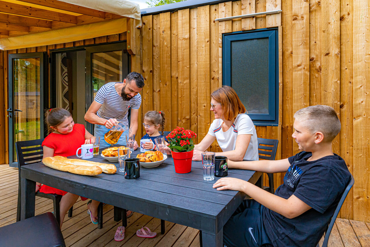 Familia desayunando en la terraza de una casa m�vil, en el camping CAPFUN Aube en Deltebre, Tarragona.