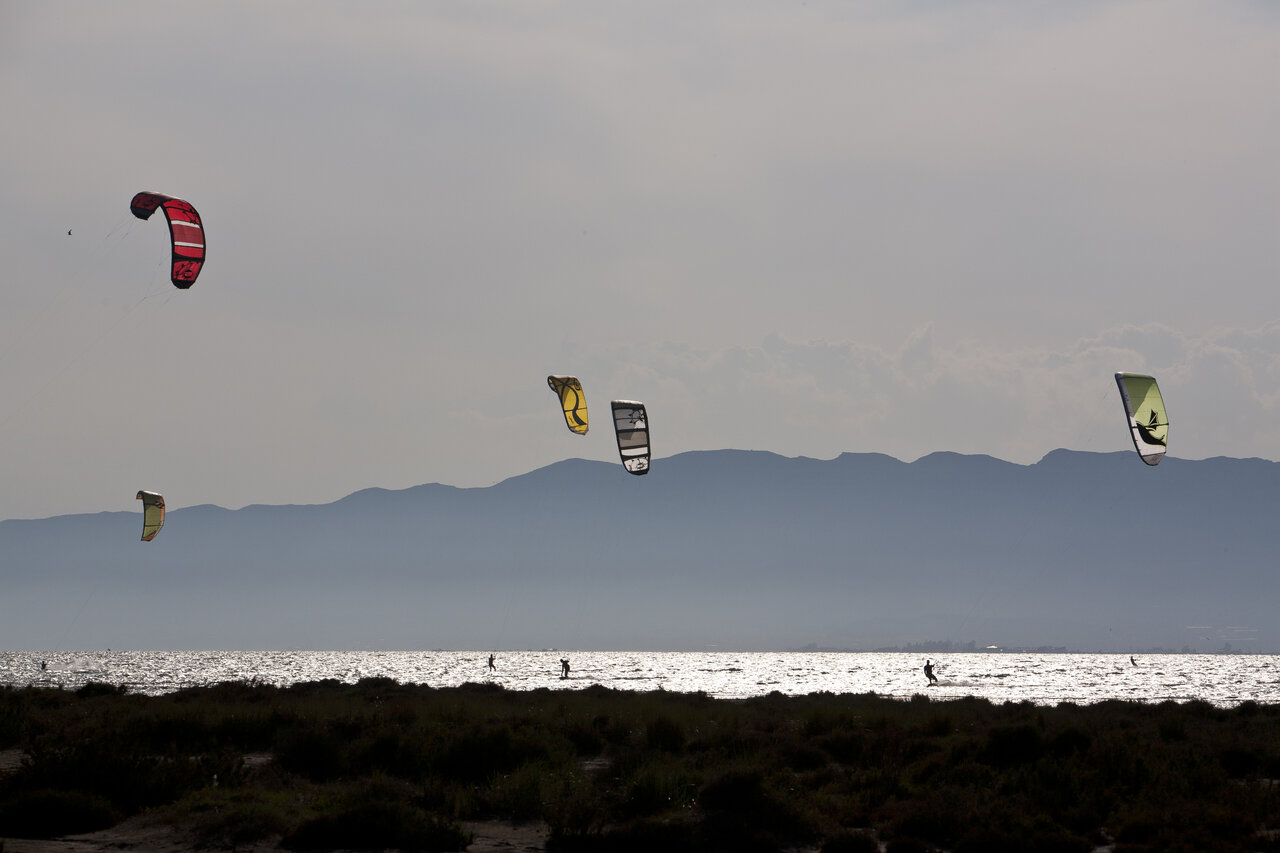 Kitesurfistas en el agua brillante con monta�as al camping CAPFUN Aube en Deltebre, Tarragona.