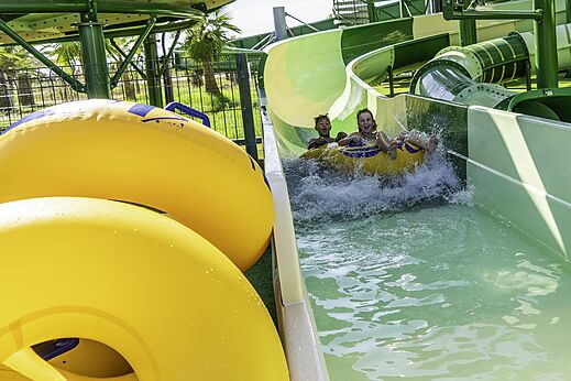 Niños en flotador bajando un tobogán acuático en el camping CAPFUN Aube en Deltebre, Tarragona.