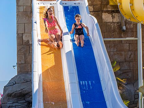 Niños bajan tobogán acuático colorido en el camping CAPFUN Aube en Deltebre, Tarragona.