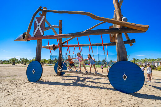 Área de juegos de madera única con niños en puente de cuerda en el camping CAPFUN Aube en Deltebre, Tarragona.