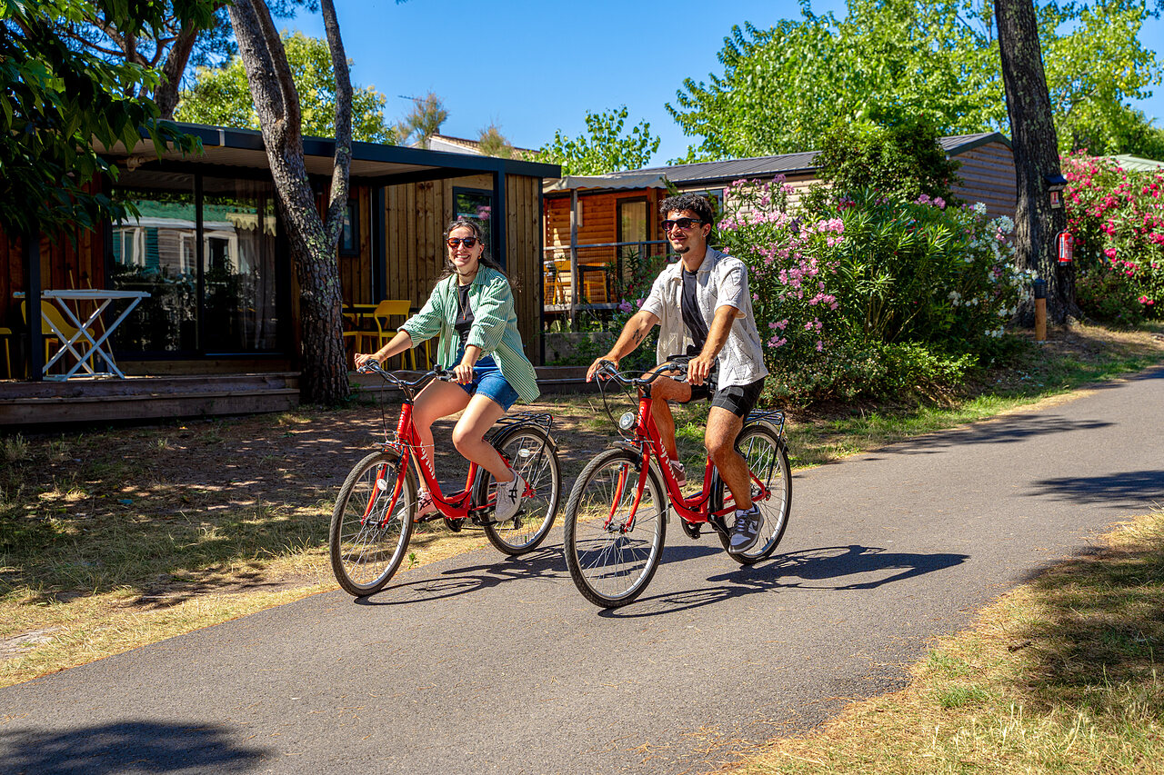 Pareja sonriente en bicicleta, casas m�viles en camping CAPFUN Aubr�des en Puget sur Argens.