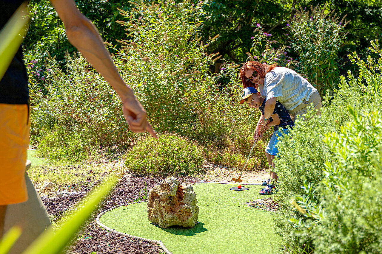 Ni�o y adulto jugando minigolf en un campo verde en el camping CAPFUN Aubr�des en Puget sur Argens (83).