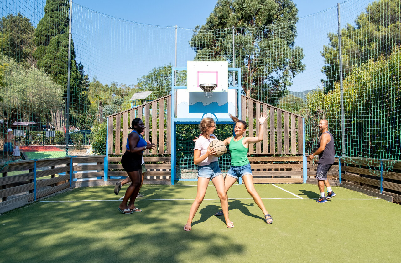 Cancha multideportiva con turistas jugando baloncesto en el camping CLICOCHIC Baie de Cavalaire.