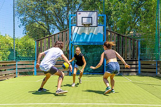 Jóvenes jugando baloncesto en la cancha multideporte del camping CLICOCHIC Baie de Cavalaire.