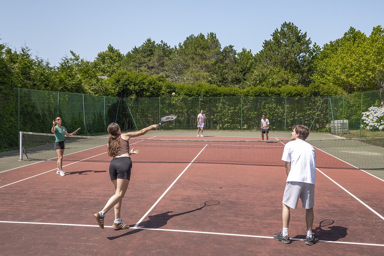 Jugadores de tenis en la cancha exterior del camping CLICOCHIC Baie de Douarnenez.
