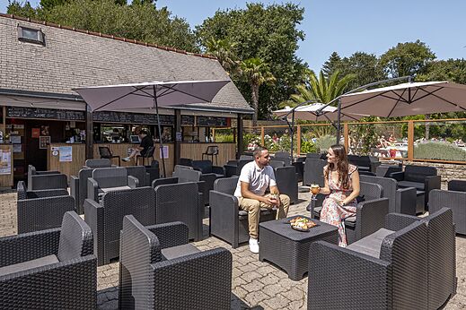 Bar exterior, terraza sombreada, pareja en el camping CLICOCHIC Baie de Douarnenez.