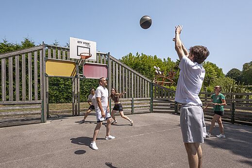 Cancha multideporte con veraneantes jugando baloncesto en el camping CLICOCHIC Baie de Douarnenez en Poullan-sur-Mer.