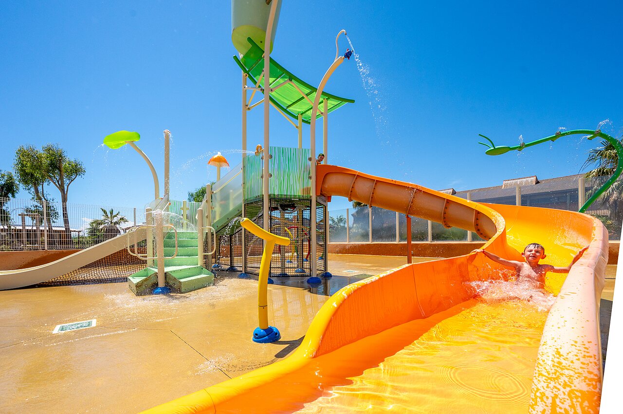 Ni�o en tobog�n acu�tico naranja, juegos de agua en camping CAPFUN Barbacane en NARBONNE (11).