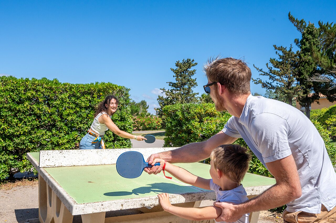 Familia jugando al ping-pong en mesa exterior, camping CAPFUN Barbacane en Narbonne.