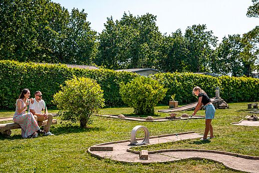 Familia jugando minigolf en un campo verde en el camping CLICOCHIC Bastets en Marsanne (26).