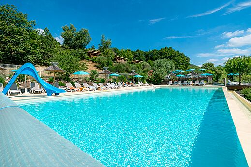 Gran piscina exterior, tobogán azul, sillas en el camping CLICOCHIC Bastets en Marsanne (26).