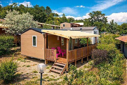 Mobil-home moderno con terraza cubierta y sillas en el camping CLICOCHIC Bastets en Marsanne (26).