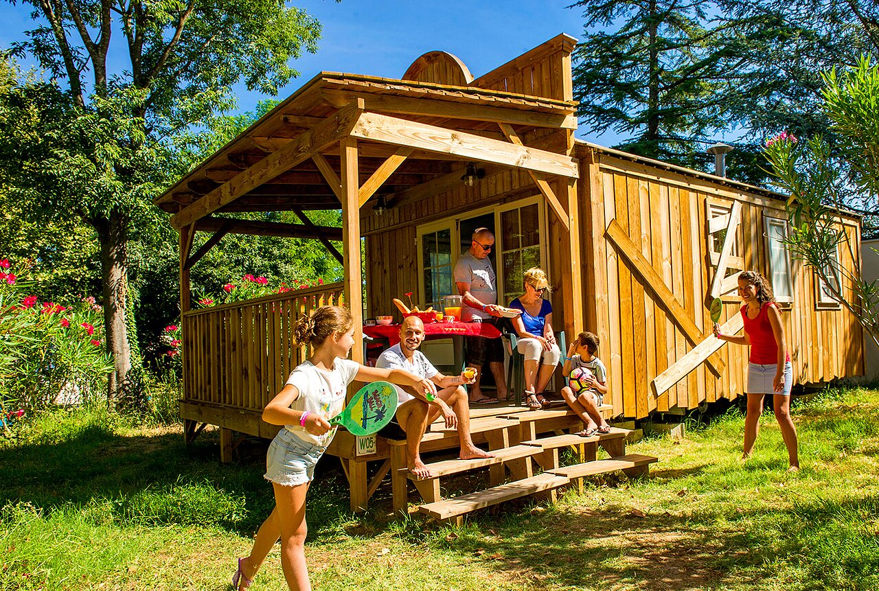 Familia disfrutando de caba�a de madera y jugando en camping CAPFUN Bastide en N�mes (30).