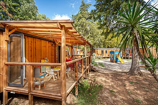 Mobil-home de madera con terraza cubierta y zona de juegos en el camping CAPFUN Bastide en Nîmes (30).