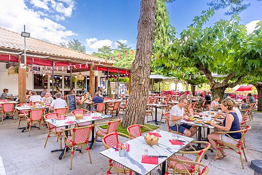 Terraza de restaurante exterior con comensales en el camping CAPFUN Bastide en Nîmes (30).