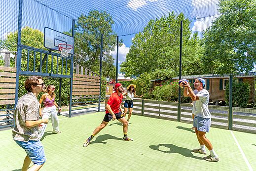 Jóvenes jugando baloncesto en cancha multideporte, camping CAPFUN Bastide Nîmes (30).