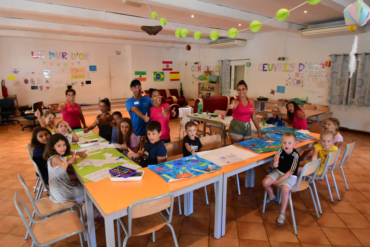 Ni�os y animadores sonrientes en una actividad creativa en el camping CAPFUN La Baume.