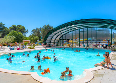 Gran piscina exterior y cubierta con bañistas en el camping CAPFUN Beauregard en MORNAS (84).