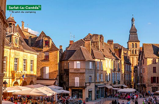Plaza animada de Sarlat-la-Can�da con edificios hist�ricos y terrazas de restaurantes.