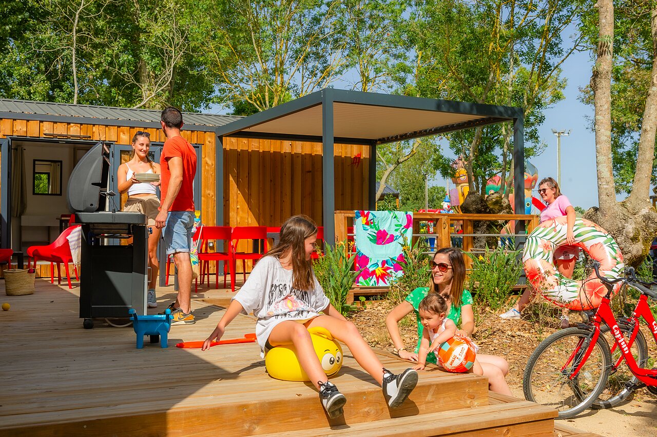 Familia disfrutando terraza mobil-home, barbacoa, flotador, camping CAPFUN Bel Air (85).