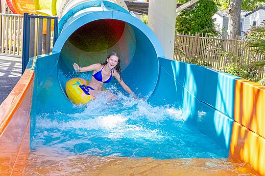 Niña en flotador bajando tobogán acuático en camping CAPFUN Bel Air en Aiguillon sur Mer (85).