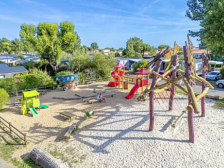 Gran área de juegos con estructuras y arena en el camping CAPFUN Bel Air en Aiguillon sur Mer (85).