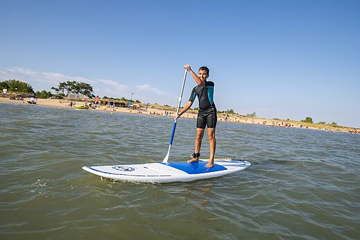 Joven en paddleboard y playa en el camping CAPFUN Bel Air en Aiguillon sur Mer (85).