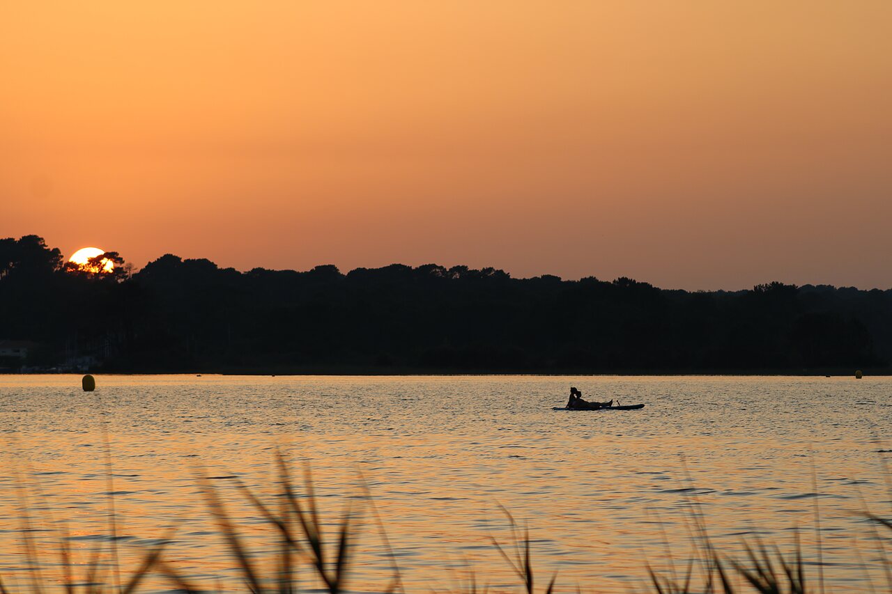 Paddleboarder en lago al atardecer, camping CLICOCHIC Bimbo en BISCARROSSE (40).